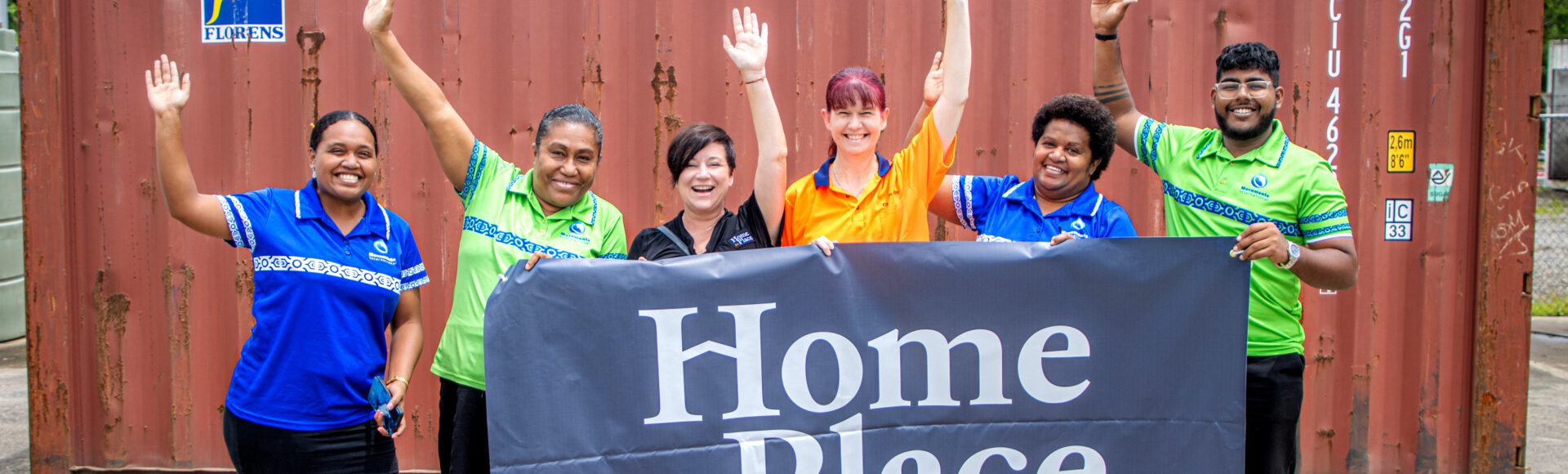 Group of people holding a banner in front of a shipping container