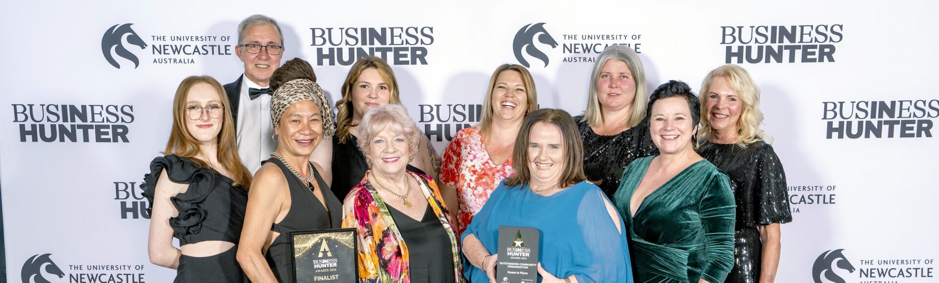 Group of ten people in front of a banner holding awards