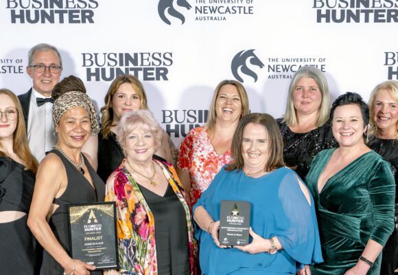 Group of ten people in front of a banner holding awards