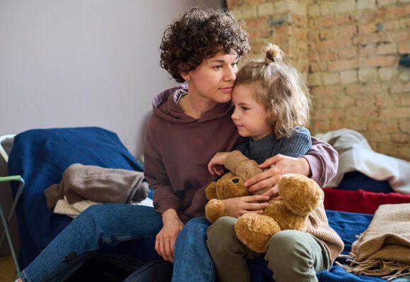 Mother and young daughter sitting on a bed