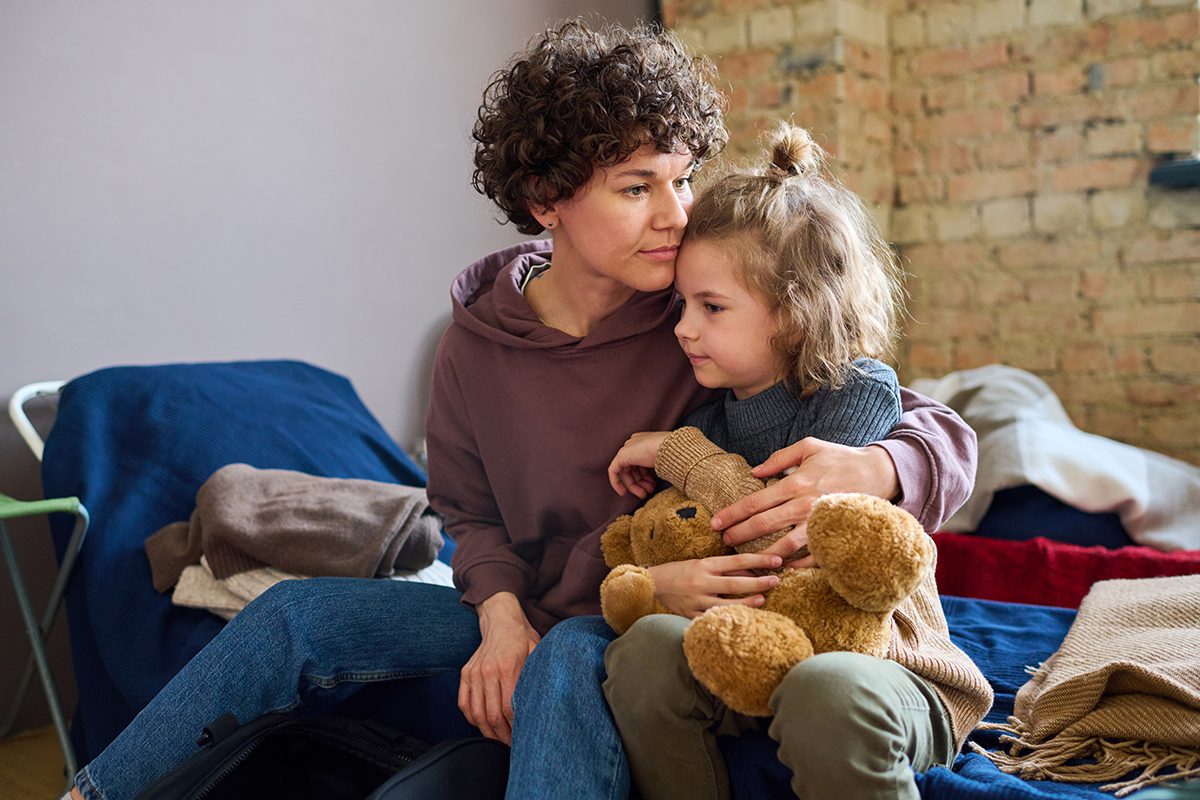 Mother and young daughter sitting on a bed