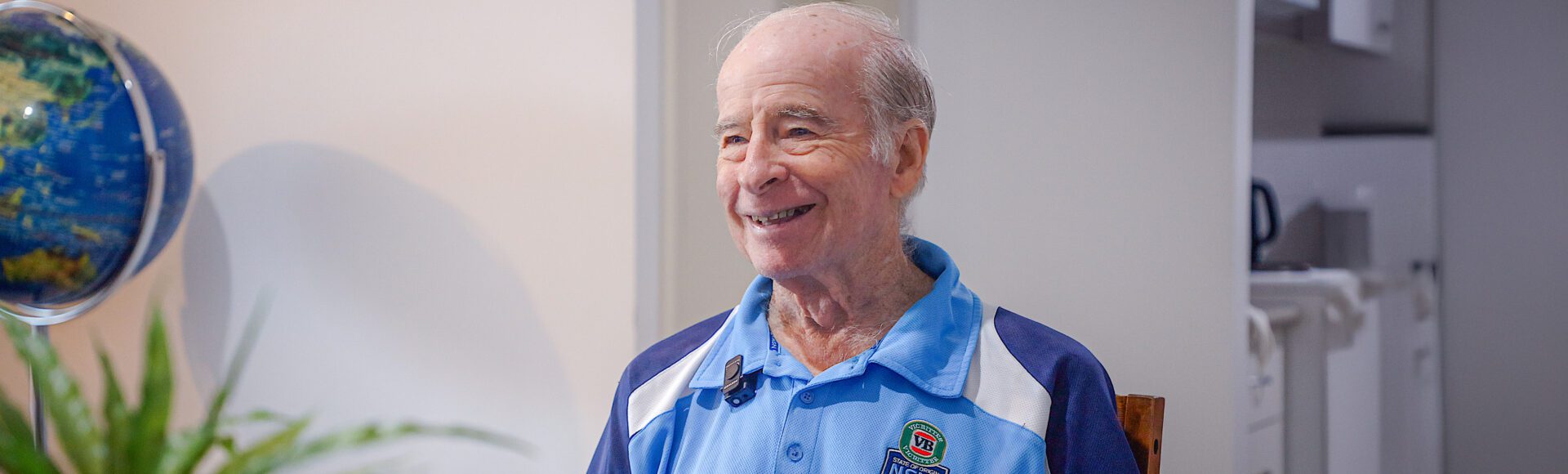 Man sitting in his lounge room looking left of camera and smiling
