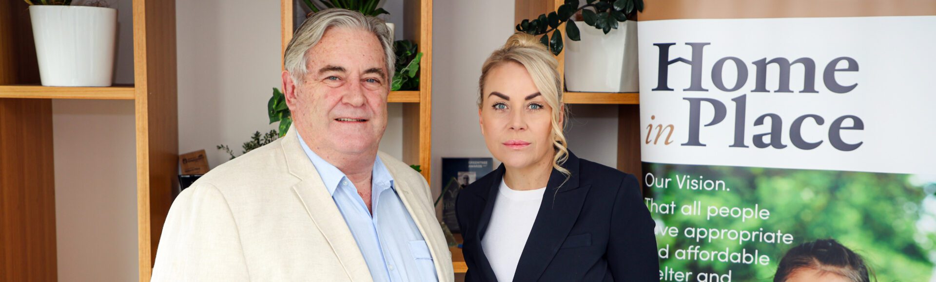 Photo of Greg Budworth and Lyndall Robertshaw in front of a Home in Place banner