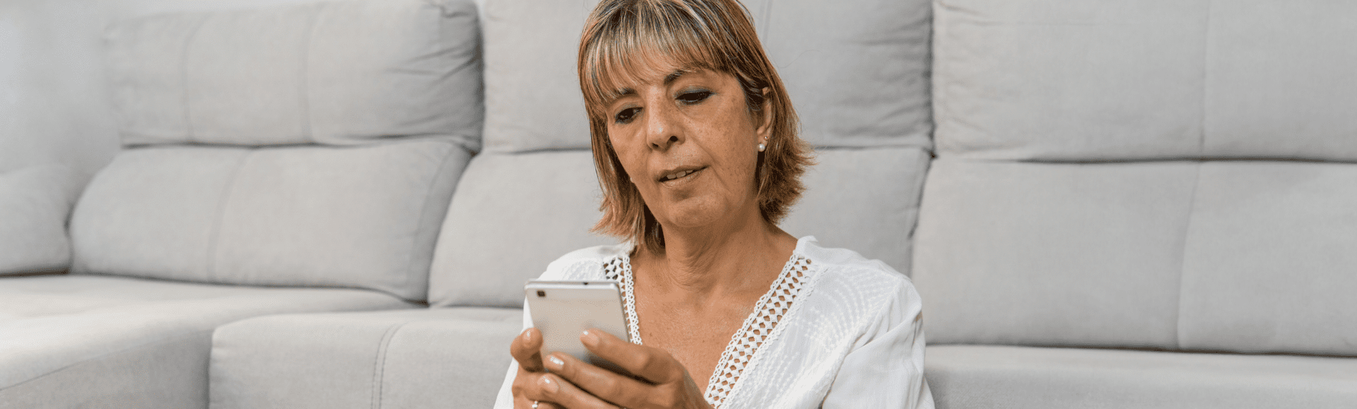 Woman sitting in her living room typing messages from her mobile phone.